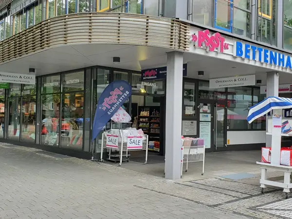 Eingang zu Bettenhaus mit SALE-Aufstellern und Bettwäsche im Schaufenster